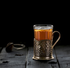 Traditional Russian tea served in glass with vintage brass glass holder. Podstakannik. Concept of tradition. Concept of tea time. Selective focus. Negative space. Copy space.