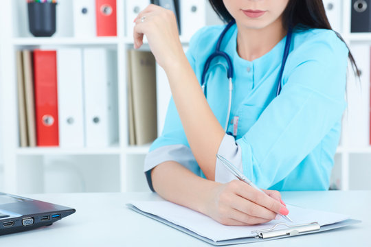 Female medicine doctor writing in a clipboard. Medical help or insurance concept. Doctor is waiting for patient to examine.