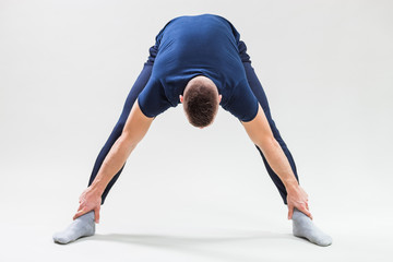 Studio shot image of young man who is stretching his body. 