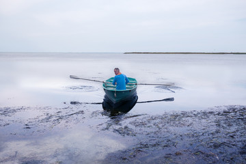 Man sailing on a small rowing boat along the sea coast