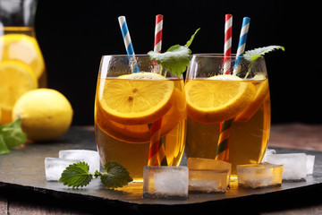 Iced tea with lemon slices, mint and ice on rustic background