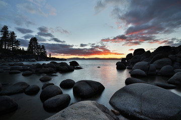 Fototapeta na wymiar Sunset at a rocky beach at the lake. Long exposure.