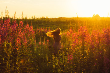 Fototapeta na wymiar Dancing beautiful girl on field, sun backlight, sunrise, orange colors, hands near the neck