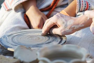 Pottery classes, student making clay pot on wheel. Close-up of dirty hands, sculpting clay crockery