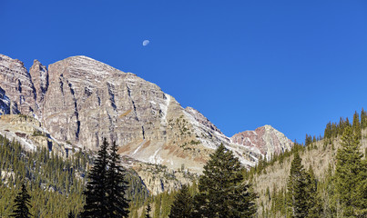 Maroon Bells mountain range with moon above, Aspen in Colorado, USA.