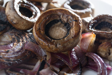 Close up of roasted juicy mushrooms with onion on white plate