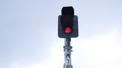 Traffic light shows red signal on railway on a gray background