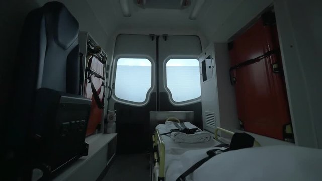 View inside of driving empty ambulance car. Ready for using stretcher with white clean bedsheet