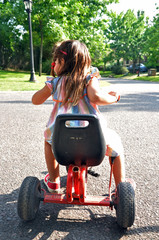 young girl on a tricycle starting to ride a bicycle in colorful dress
