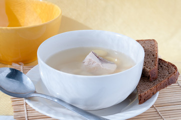 Spoon near a plate of fish soup with black bread  