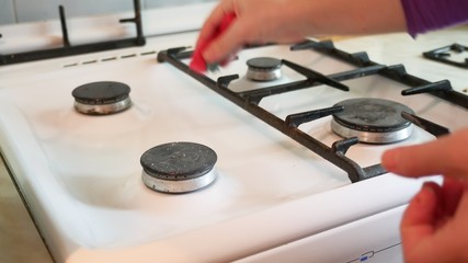 woman washes a gas stove in cleaning the kitchen