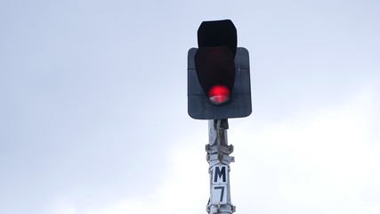Traffic light shows red signal on railway on a gray background