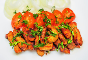 Fried pieces of pork schnitzel with cherry tomatoes and onion rings