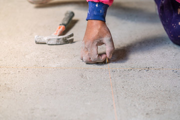 Hand hold nail hit on concrete floor for plane laying ceramic tiles, installing tiles in construction site.
hammer ready to work on cement floor.