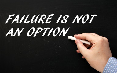 Male hand in a business shirt writing the words Failure Is Not An Option on a blackboard as a motivation statement for success