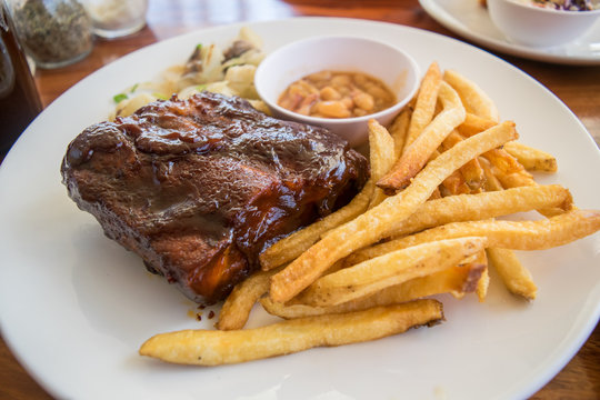 half rack of barbecue pork ribs with french fries on plate
