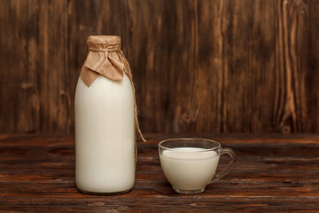 Bottle of milk and cup on rustic wooden table