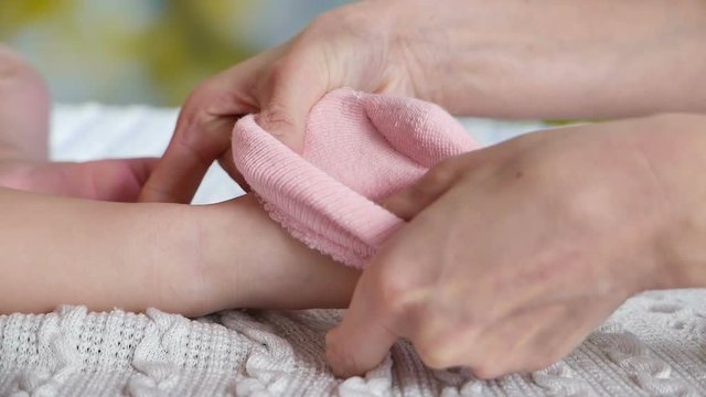 Mother putting pink socks on baby's feet