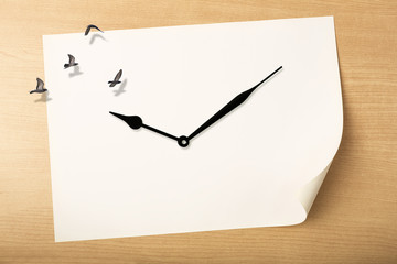 Time fly concept, Travel time concept, clock with birds flying above white paper on wood background