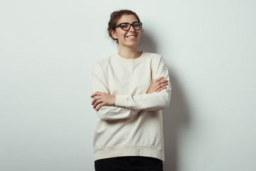 Handsome smiling woman hipster wearing blank sweater and eye glasses. Empty studio wall background
