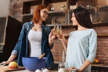 Attractive positive females clinking glasses