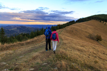 Fototapeta na wymiar Young couple hiking outdoors with backpacks during sunset