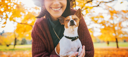 Closeup on happy young woman with dog outdoors in autumn