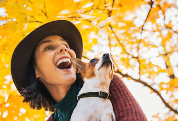 happy young woman with dog outdoors in autumn lookin