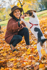 Fototapeta premium Young woman playing with dog outdoors in autumn