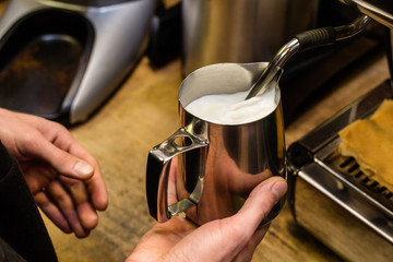 Barista preparing milk for takeaway coffee.