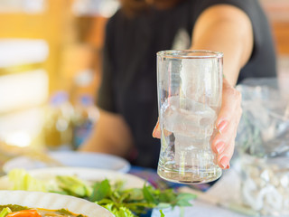 Woman hand holding a glass with ice. Flare light.