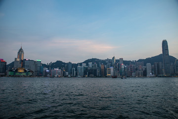 Obraz premium Hong Kong, China skyline panorama from across Victoria Harbor. Hong Kong city skyline view from harbor with skyscrapers buildings reflect in water at sunset
