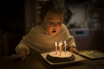 誕生日ケーキのロウソクを吹き消そうとする女の子