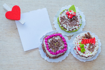 Close up small cakes on wood with blank white paper and red clip paper heart  for background/texture.Designer concept.