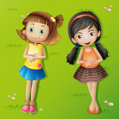 Two girls lying back on green grass