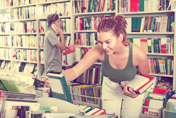 girl teenager choosing book in shop .