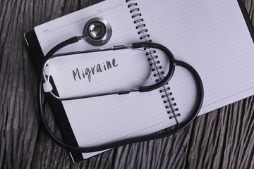 "Migraine" Word on Note book With Stethoscope on wooden backgrou