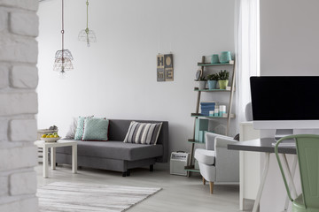 Living room with grey sofa, coffee table and white armchair