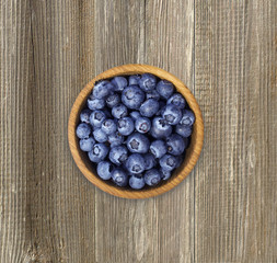 Blueberries in a wooden bowl. Top view. Ripe and tasty blueberries on a wooden background.