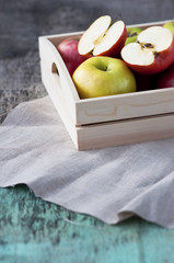 Fresh apples in a wooden box on a wooden background. Apples are red, green, yellow. Healthy Eating Vitamins Vegetarian Seasonal harvest.