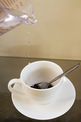 Pour hot water in a cup of white coffee.