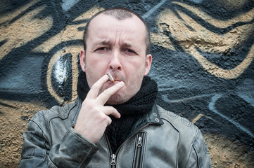 homme et cigarette en extérieur devant un mur de graffiti
