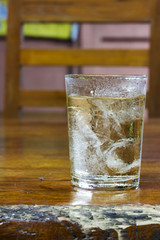 Drinking water in the glass on a wooden table.