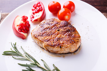 Grilled steak with tomatoes and pomegranate on white dish