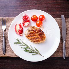 Grilled steak with tomatoes and pomegranate on white dish