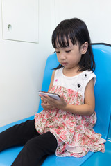 Asian Chinese little girl sitting inside a MRT with phone