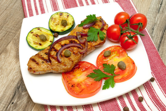 juicy grilled steak with vegetables on the plate on a wooden tab