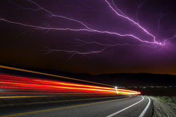 Lighting strike with long exposure traffic trails under stormy sky.