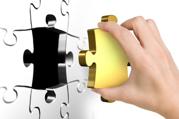 Hand holding last missing golden puzzle piece