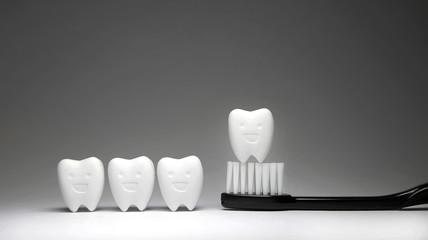 Fototapeta na wymiar Tooth model in happy emotion and black toothbrush , if brush the teeth, teeth will good healthy